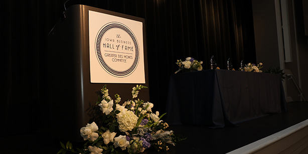 A podium with a poster that says "Iowa Business Hall of Fame" with flowers below it